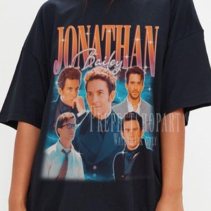 May include: Black oversized t-shirt with a vintage-style graphic print of a band called "Jonathan Bailey". The print features five men in a blue and orange color scheme with lightning bolts.