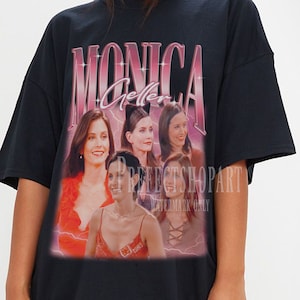 May include: Black oversized t-shirt with a graphic print of Monica Geller from the TV show Friends. The graphic features a collage of Monica's face in different poses with a pink and purple "Monica Geller" text.