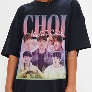 May include: Black oversized t-shirt with a graphic print of a group of men with the text "CHOI Woo Shik" in pink and blue lettering.