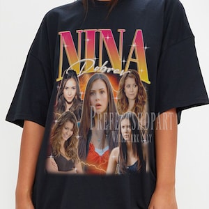 Puede incluir: Camiseta negra de gran tamaño con un gráfico de estilo vintage de Nina Dobrev de la serie de televisión "The Vampire Diaries". El gráfico es un collage de imágenes de Dobrev en diferentes escenas de la serie, con el texto "Nina Dobrev" en una fuente en negrita y colorida.