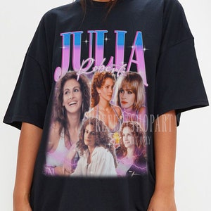 May include: Black oversized t-shirt featuring a graphic print of Julia Roberts in a collage of images from different films. The text "Julia Roberts" is printed in pink and blue on the shirt.