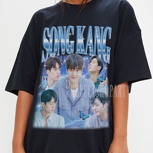 Könnte beinhalten: Schwarzes Oversize-T-Shirt mit einem Grafikdruck einer Gruppe von Männern mit dem Text "Song Kang" in blauen und weißen Buchstaben.