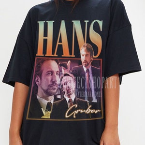 May include: Black oversized t-shirt with a graphic print of a man's face and the text "Hans Gruber".