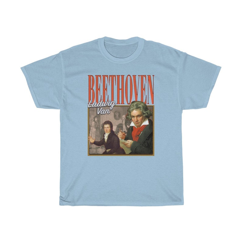 Pu&ograve; includere: T-shirt blu chiaro con una grafica in stile vintage di Ludwig van Beethoven. La grafica presenta un ritratto di Beethoven e il testo "BEETHOVEN Ludwig Van" in rosso e bianco.