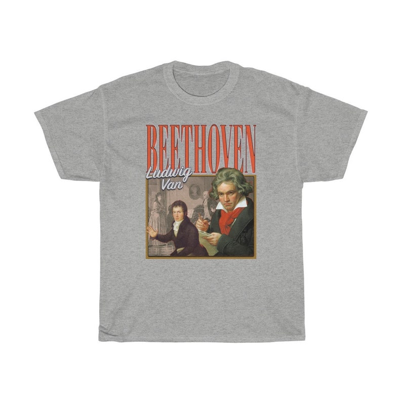 Pu&ograve; includere: Una t-shirt grigia con una grafica in stile vintage di Ludwig van Beethoven. La grafica presenta un ritratto di Beethoven e il testo "BEETHOVEN Ludwig Van" in rosso e bianco.