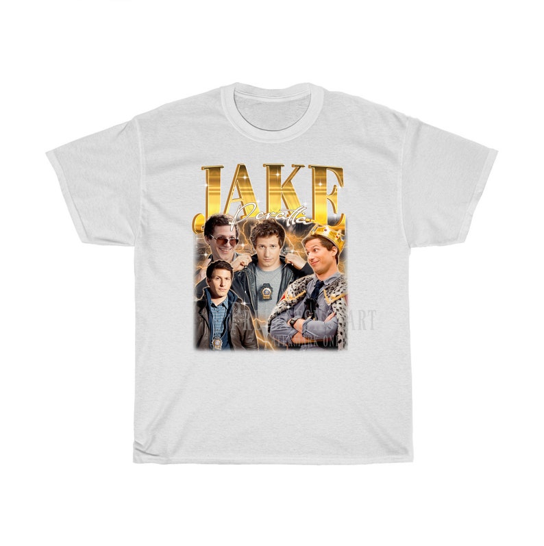 May include: White t-shirt with a gold graphic of Jake Peralta from the TV show Brooklyn Nine-Nine. The graphic includes the text "JAKE" and "Peralta" in gold letters.