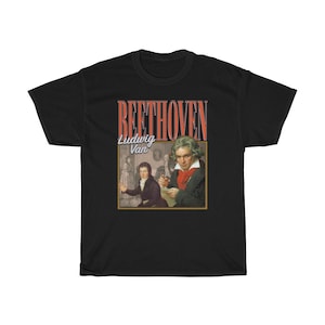 Pu&ograve; includere: T-shirt nero con una grafica in stile vintage di Ludwig van Beethoven. La grafica presenta un ritratto di Beethoven e il testo "BEETHOVEN" in rosso e bianco.