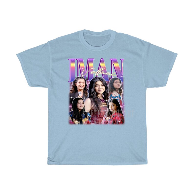 May include: Light blue t-shirt with a retro-style graphic featuring a group of four girls. The graphic includes the text "IMAN" in a purple and pink font.