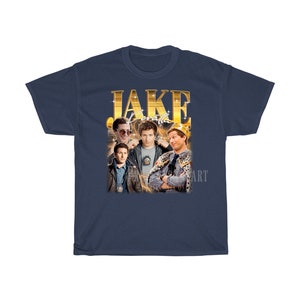 May include: A navy blue t-shirt with a gold graphic of Jake Peralta from the TV show Brooklyn Nine-Nine. The graphic features Jake Peralta in different poses, including wearing a crown.
