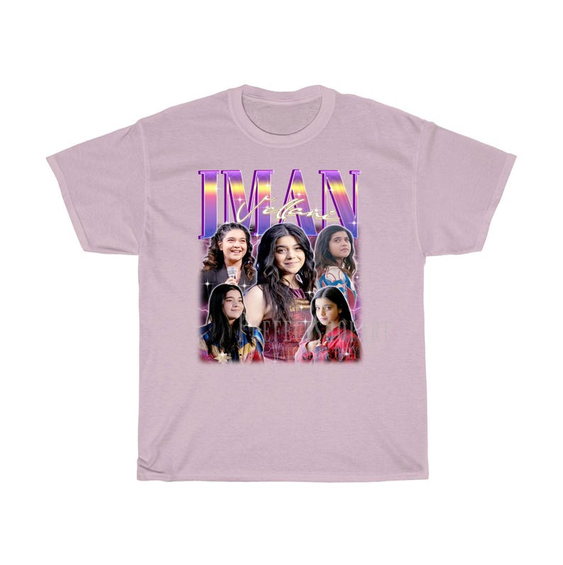 May include: A light purple t-shirt with a retro-style graphic featuring a group of four people. The graphic includes the text "IMAN" in a purple and blue gradient. The people in the graphic are all women with dark hair and are wearing colorful clothing.