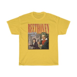 Pu&ograve; includere: Maglietta gialla con una grafica in stile vintage di Ludwig van Beethoven. La grafica presenta un ritratto di Beethoven e il testo "BEETHOVEN Ludwig Van".
