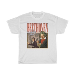 Pu&ograve; includere: Maglietta bianca con una grafica in stile vintage di Ludwig van Beethoven. La grafica presenta un ritratto di Beethoven e il testo "BEETHOVEN Ludwig Van" in rosso.