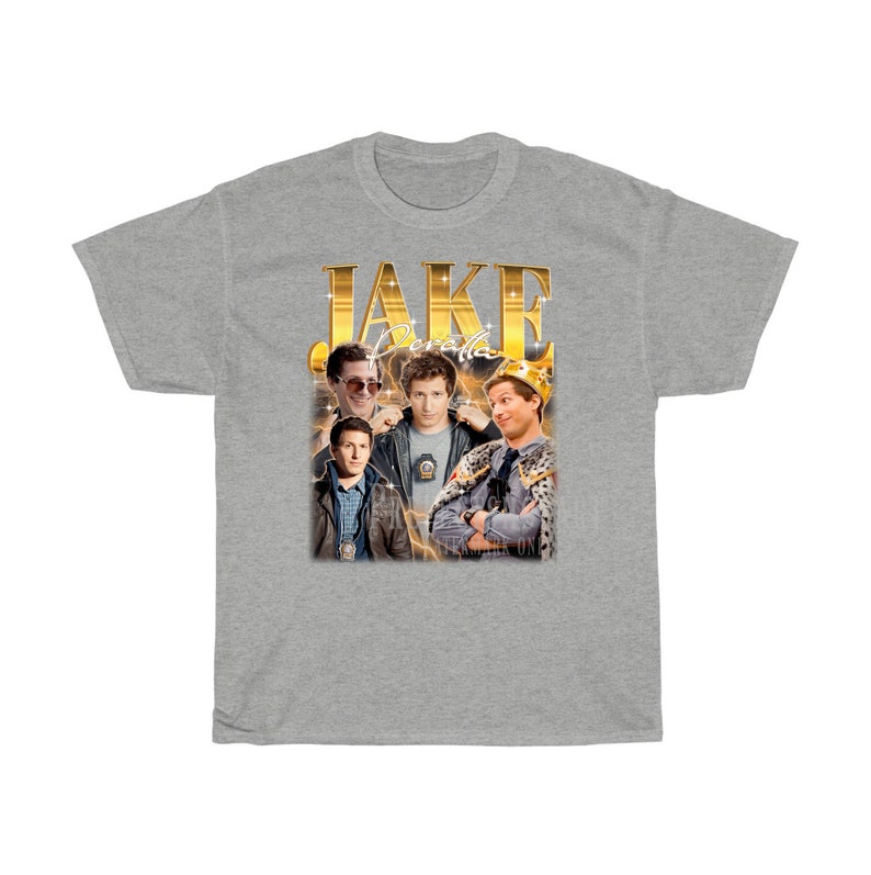 May include: A gray t-shirt with a gold graphic of Jake Peralta from the TV show Brooklyn Nine-Nine. The graphic includes the text "JAKE" and "Peralta" in gold lettering.