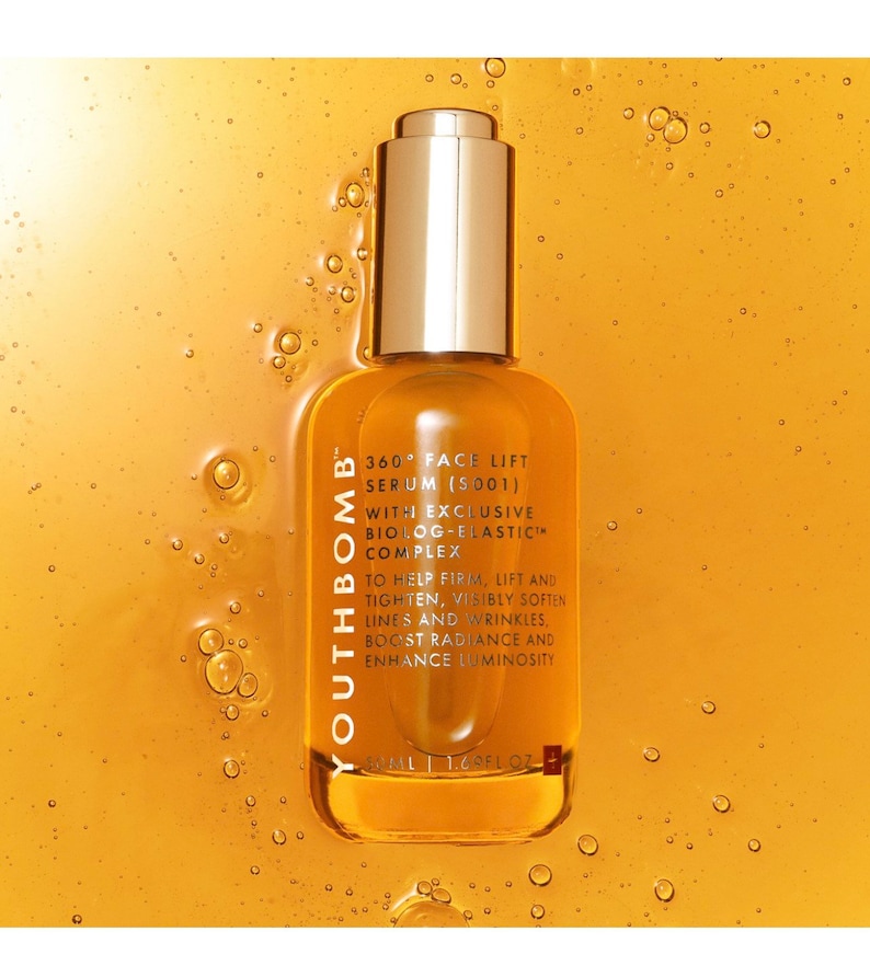 May include: A glass bottle of Youthbomb 360&deg; Face Lift Serum (SO01) with an exclusive Biolog-Elastic Complex. The bottle is gold and has a dropper top. The text on the bottle reads "To help firm, lift and tighten, visibly soften lines and wrinkles, boost radiance and enhance luminosity."