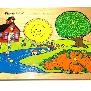 Op de afbeelding: Houten Fisher-Price puzzel met een schoolgebouw, een lachende zon, een boom en pompoenen. De puzzel heeft een rivier met boten en spelende kinderen. De puzzel is ontworpen voor kinderen van 2-5 jaar.