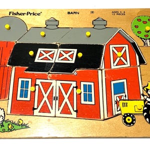 Op de afbeelding: Een houten Fisher-Price boerderijpuzzel met 12 stukjes voorzien van gele knoppen. De afbeelding toont een rode schuur, een silo, een tractor, een boom en kippen. De tekst op het bord vermeldt Fisher-Price, BARN en AGES 3-6 12 PIECES.