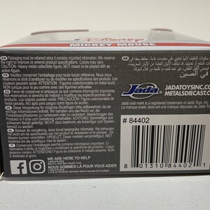May include: A black and gray box with text including "MICKEY MOUSE" and "Jada Toys." The box has a barcode and the number 84402. The box contains a collectible figure.