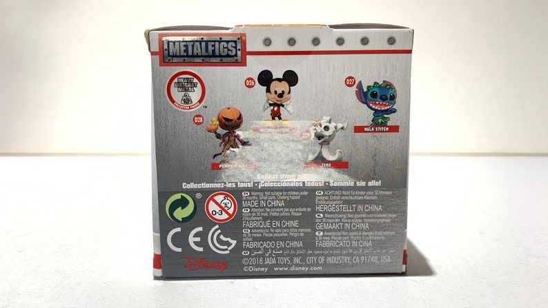 May include: A box featuring Disney characters from the Metalfigs collection. The box displays images of Mickey Mouse, Jack Skellington, Zero, and Stitch. The box has the Metalfigs logo and the Disney logo.