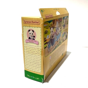 May include: A yellow Sylvanian Families cardboard toy box featuring a Pookie Panda Girl character named Rosalina. The packaging displays illustrations of panda figures on a bicycle, descriptive text about the characters, and the Sylvanian Families logo.