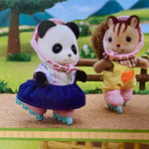 May include: Two anthropomorphic animal figures, a panda and a squirrel, wearing pink helmets and roller skates. The panda wears a striped top and a dark blue skirt, while the squirrel wears a yellow overall with a checkered collar and pink pants.