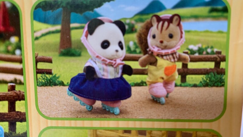May include: Two anthropomorphic animal figures, a panda and a squirrel, wearing pink helmets and roller skates. The panda wears a striped top and a dark blue skirt, while the squirrel wears a yellow overall with a checkered collar and pink pants.