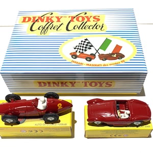 May include: Two red toy race cars, a Ferrari and a Maserati, in their original boxes. The boxes are yellow with black text and feature the Dinky Toys logo. The cars are part of a collector's set.