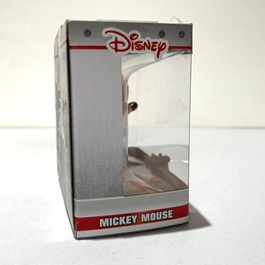 May include: A Disney-branded product box with a clear plastic window. The box is primarily white with red and gray accents. The Disney logo is visible at the top, and the words "Mickey Mouse" are printed on the bottom.