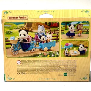 May include: A Sylvanian Families toy set box featuring a panda figure on a light blue bicycle with a matching trailer. The box displays various scenes of animal figures, including a panda, a wolf, and a rabbit, engaged in outdoor activities.