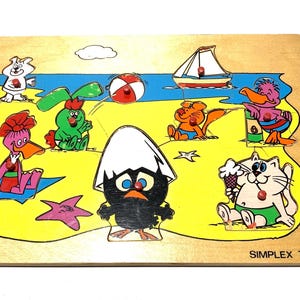 Op de afbeelding: Houten legpuzzel met een strandscène met cartoon dieren. De puzzel bevat een zeilboot, een strandbal en verschillende personages zoals een eend, een kat en een konijn. Gemaakt door Simplex Toys.