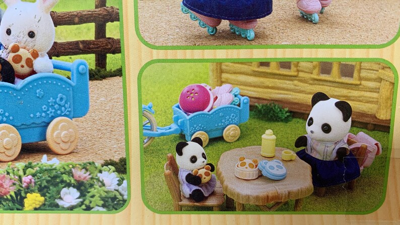 May include: A set of miniature flocked animal figures including a white rabbit and two pandas. The scene features a blue toy wagon, a wooden-style table with small food items, a yellow bottle, and a small chair, all displayed on a green surface.
