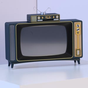 Könnte beinhalten: Ein dunkelblaues Fernsehgerät mit Goldverzierungen, einem rechteckigen Bildschirm und vier kleinen Standfüßen. Ein kleineres rechteckiges Gerät mit einer silbernen Antenne steht oben auf dem Fernseher. Das Gerät hat vertikale silberne Streifen.