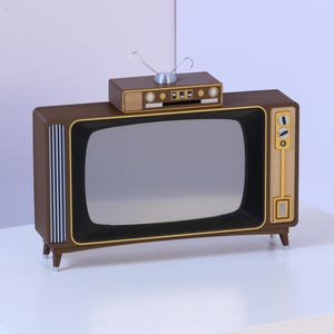 May include: A brown television set with a rectangular screen, gold-toned control panel, and vertical silver slats on the left side. A smaller brown rectangular box with a silver antenna sits on top of the television, which stands on four legs.