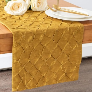 May include: A gold table runner with a quilted pattern. The runner is made of a soft, luxurious fabric and is perfect for adding a touch of elegance to any table setting.