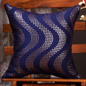 May include: A navy blue throw pillow with a geometric pattern of silver and gold sequins.