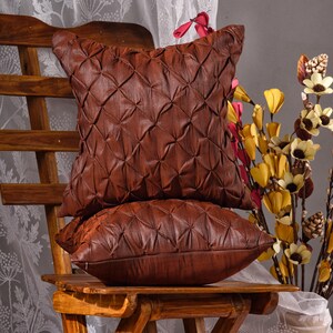 May include: Two brown quilted pillow covers with a diamond pattern. The pillow covers are sitting on a wooden chair.