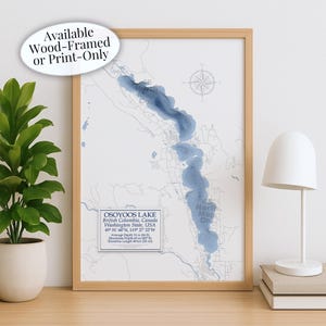 May include: A framed print of Osoyoos Lake, featuring a blue and white topographic map design. The print details the lake's location in British Columbia, Canada, and Washington State, USA. Text on the print reads "Available Wood-Framed or Print-Only."
