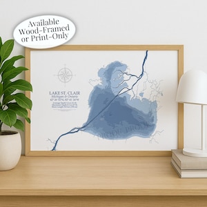 May include: A framed print of Lake St. Clair, Michigan & Ontario, featuring a light blue topographical map. The print includes the lake's coordinates, average and maximum depths, and shore length. The text "Available Wood-Framed or Print-Only" is at the top.