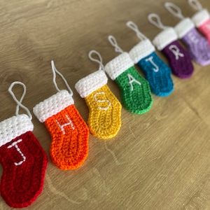 May include: A set of nine crocheted Christmas stockings in rainbow colours with white felt letters spelling out the word "SANTA".