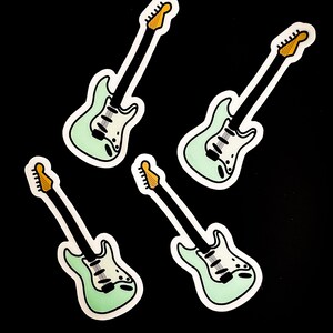 May include: Four mint green electric guitar stickers with black outlines and yellow tuning pegs. The stickers are on a black background. The text "jaybird lane" is in the bottom right corner.