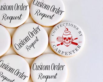 May include: White, round cookies with the text "Custom Order Request" in black script. One cookie features a red skull logo with the text "Confections by Carpenter" and the year "2017".