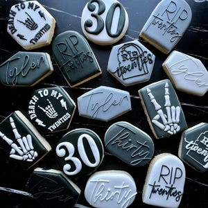 May include: An assortment of decorated sugar cookies with dark gray and white icing. Some cookies have the number "30", the words "Tyler", "Thirty", "Death to my twenties", and "RIP twenties". Other cookies feature a skeleton hand.