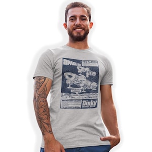 May include: A grey t-shirt featuring a vintage-style print of a spaceship and the text "Space: 1999 Red Alert!! Another Dinky Exclusive Dinky Die Cast Toys".