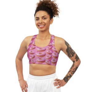 Könnte beinhalten: Rosa Sport-BH mit Donut-Muster. Der BH hat einen Racerback-Stil und ist aus einem dehnbaren, bequemen Stoff gefertigt.
