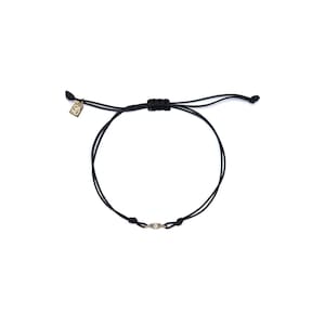 May include: A black string bracelet with a small gold charm featuring a single clear stone.