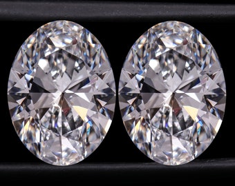 May include: Two round, clear, brilliant cut diamonds are displayed on a black surface.