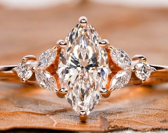 May include: A rose gold engagement ring featuring a large marquise-shaped diamond and smaller pear-shaped diamonds on the band.