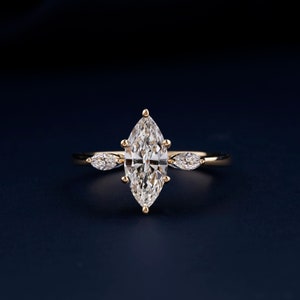 Pu&ograve; includere: Un anello d'oro con un grande diamante a forma di marquise al centro e due diamanti pi&ugrave; piccoli a forma di pera su entrambi i lati.