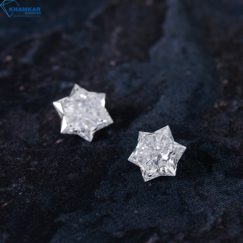 May include: Two clear, star-shaped diamonds on a black fabric background.
