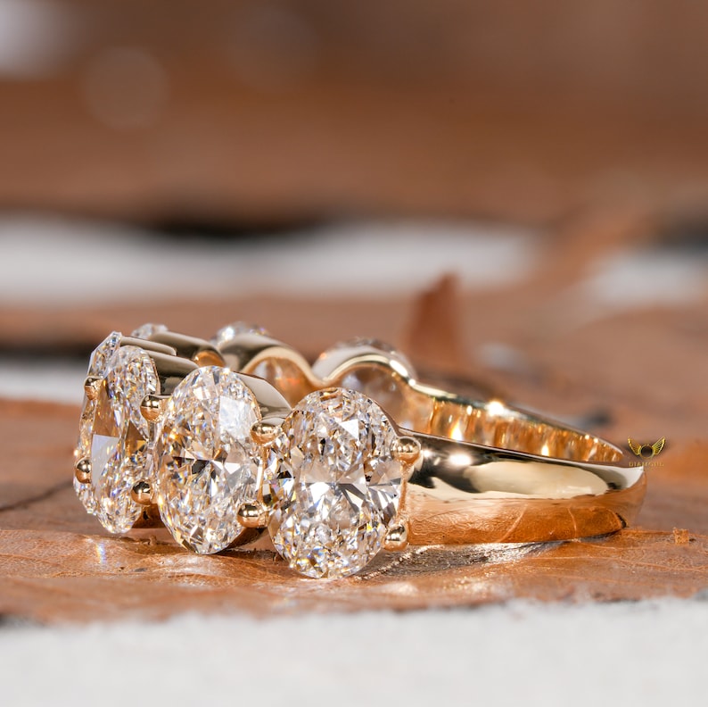 May include: A gold band ring with four oval-shaped diamonds set in a pave setting.