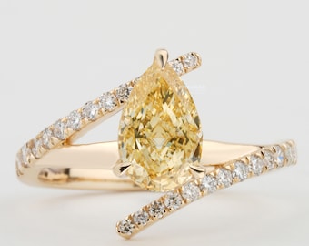 May include: A gold ring with a pear-shaped yellow diamond set in the center. The ring is accented with smaller diamonds set in a pave setting along the band.